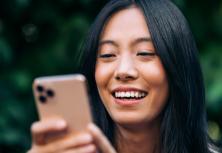 woman outside smiling looking at smartphone